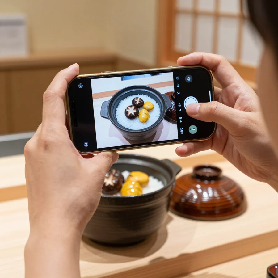 スマホで釜めしの写真を撮っている手元